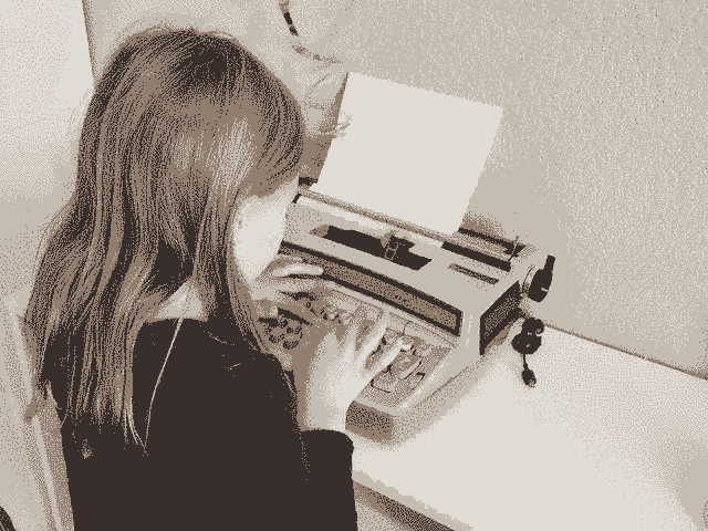 Little girl typing on a baby blue typewriter